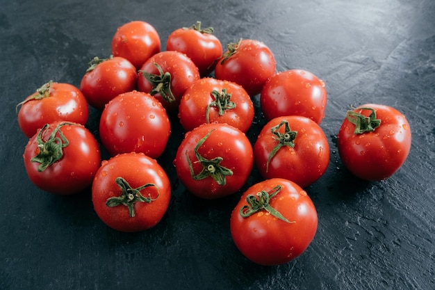 Ripe fresh red organic tomatoes being wet and clean isolated over black background Detailed close up shot Selective focus