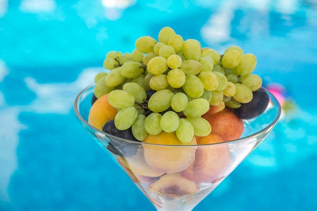 Ripe fruit in a glass vase near pool