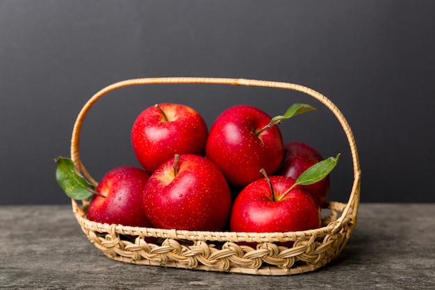 Ripe garden apple fruits with leaves in basket on wooden table. Top view flat lay with copy space