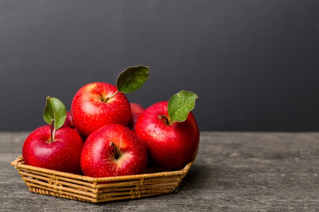 Ripe garden apple fruits with leaves in basket on wooden table. Top view flat lay with copy space