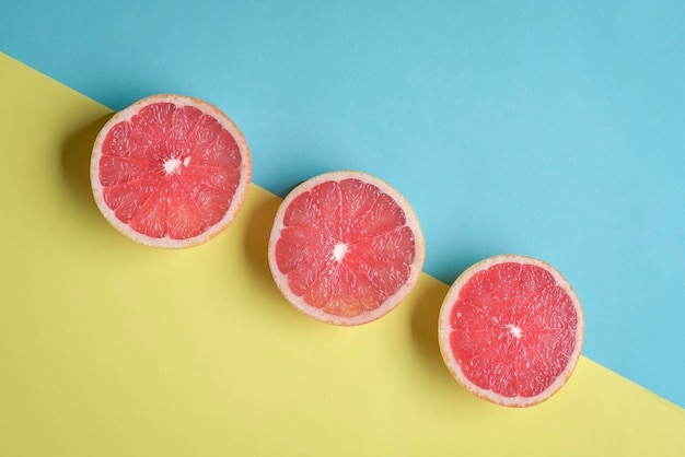 Ripe grapefruit halves on blue and yellow background