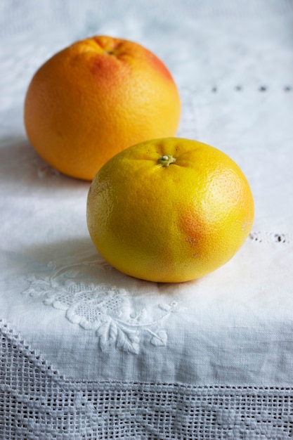 Ripe grapefruits on a white screwed tablecloth. Selective focus.