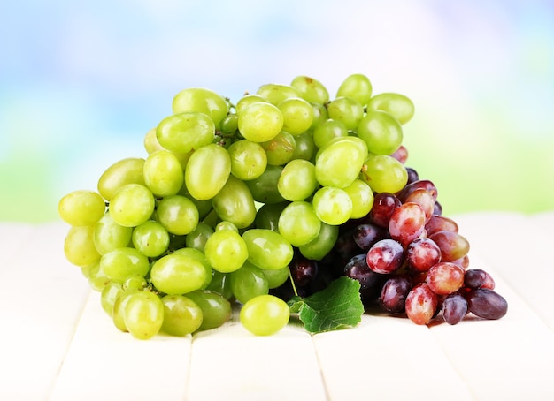 Ripe green and purple grapes on wooden table on natural background