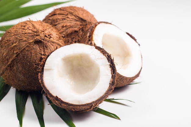 Ripe half cut coconut with green leaves on a white background. Isolated concept.