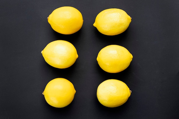 Ripe juicy lemons on a black background Lemon fruit citrus minimal concept vitamin C Creative minimalistic background