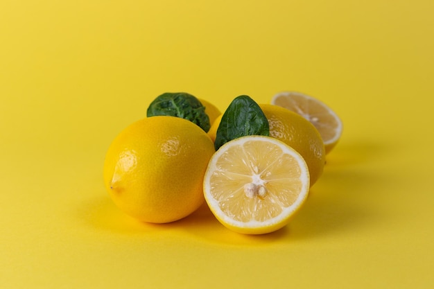 Ripe juicy lemons orange and green leaves on bright yellow background Lemon fruit citrus minimal concept vitamin C Creative summer minimalistic background Flat lay top view copy space