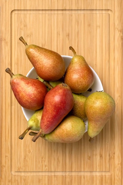 Ripe juicy pears in a bowl on a wooden background