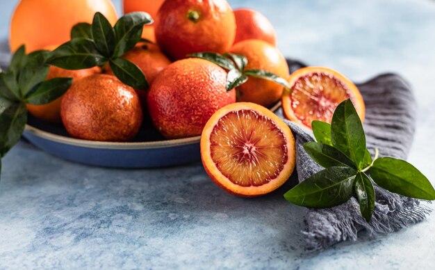 Ripe juicy Sicilian blood oranges with leaves on ceramic plate