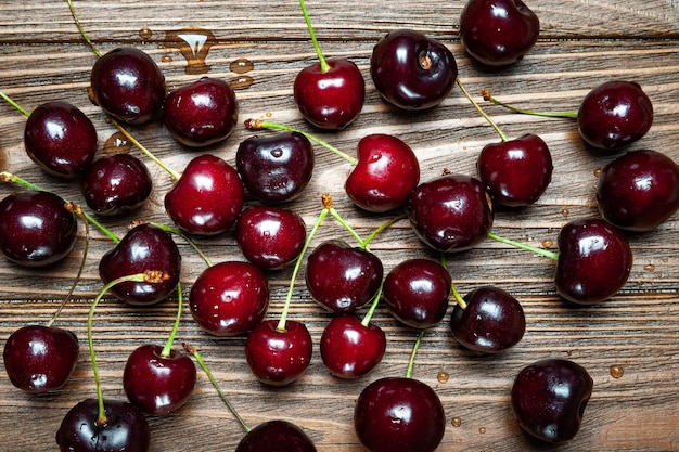 Ripe juicy sweet cherries on a wooden background Top view wet fresh cherries with water drops