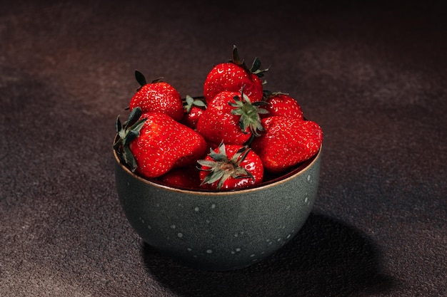 Ripe juicy tasty strawberries in a bowl on a brown background