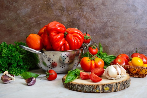 Ripe juicy tomatoes of different varieties green fragrant basil garlic on the table Italian Cuisine