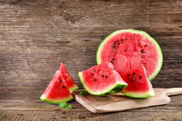 Ripe juicy watermelon pieces on wooden background.