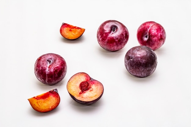 Ripe large purple plums. Fresh whole fruits, half sliced, seeds.