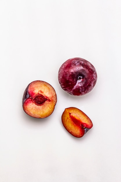 Ripe large purple plums. Fresh whole fruits, half sliced, seeds.