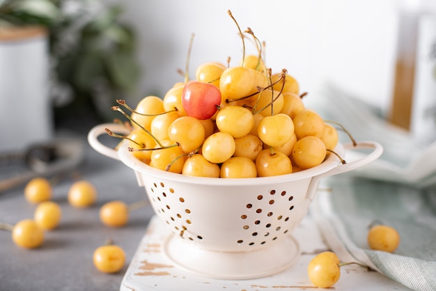 Ripe large yellow cherries in a small colander