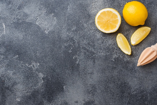 Ripe lemon and lemon slices on grey surface .