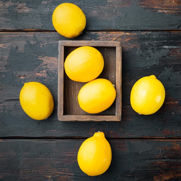 Ripe lemons set, in wooden box, on dark wooden background