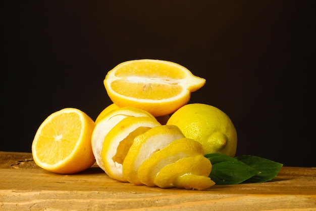 Ripe lemons with leaves on wooden table on brown background