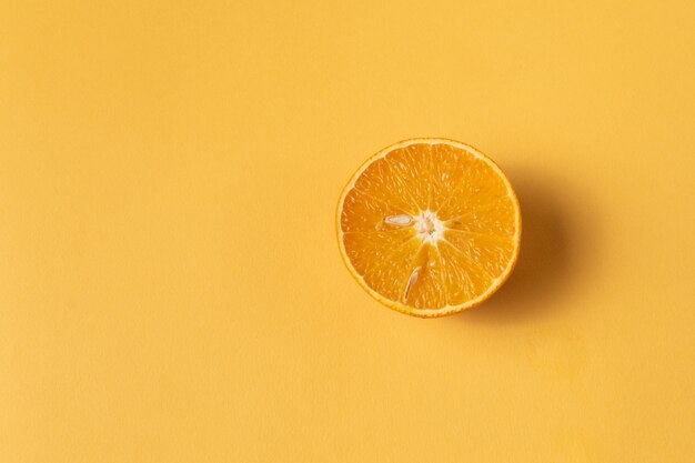 Ripe mandarin or tangerine fruit cut in half over yellow background.