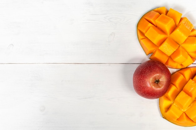 Ripe mango and apples on white wooden table