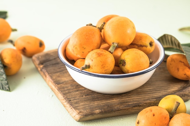 Ripe medlar fruit Eriobotrya japonica and green medlar leaves on wooden table Top view