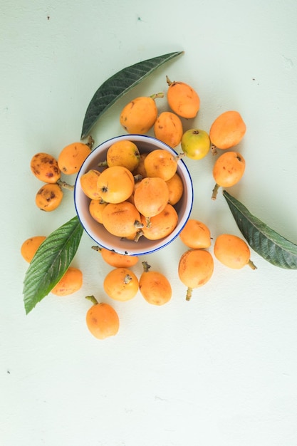 Ripe medlar fruit Eriobotrya japonica and green medlar leaves on wooden table Top view