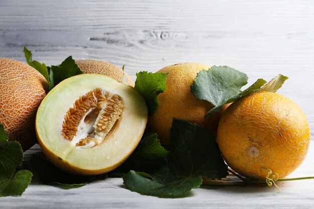 Ripe melons with green leaves on wooden background