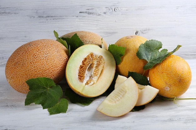 Ripe melons with green leaves on wooden background