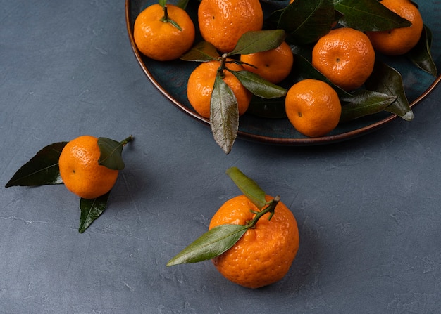 Ripe orange tangerine in a plate on a grey background macro