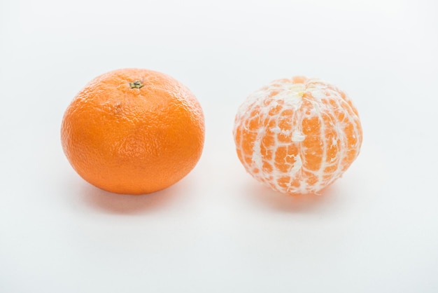 Ripe orange whole peeled and unpeeled tangerines on white background