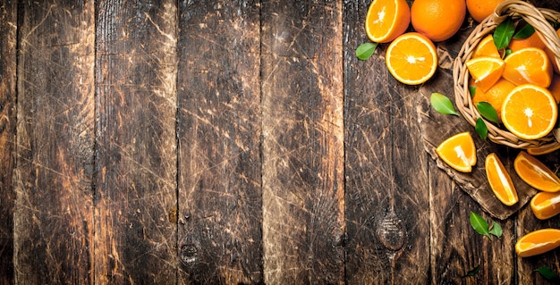 Ripe oranges in the basket on wooden background