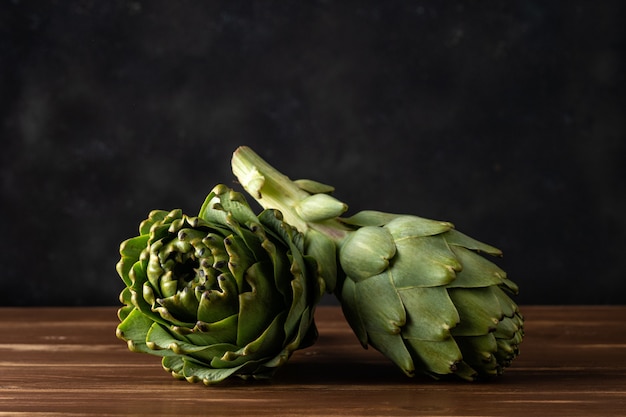 Ripe organic artichokes on a rustic wooden table.