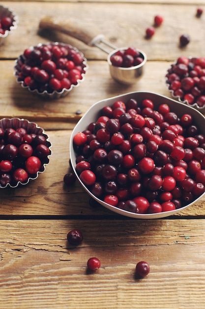 Ripe organic cranberry on rustic wooden table fresh berries in bowls autumn harvest concept