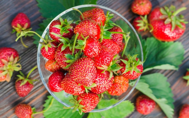 Ripe organic strawberries in a glass vase on a wooden table