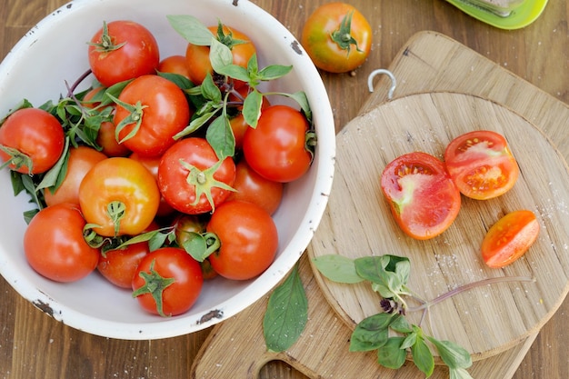 Ripe organic tomatoes in bowl on wooden table