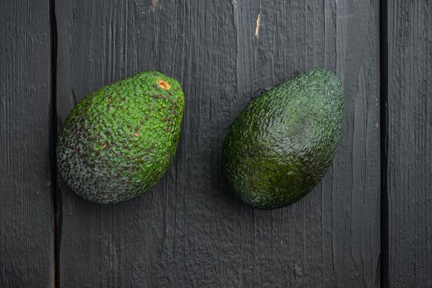 Ripe pair of green avocado set, on black wooden table, top view or flat lay