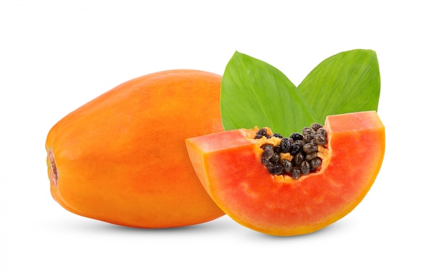 Ripe papaya fruit with seeds and leaves on white wall. 