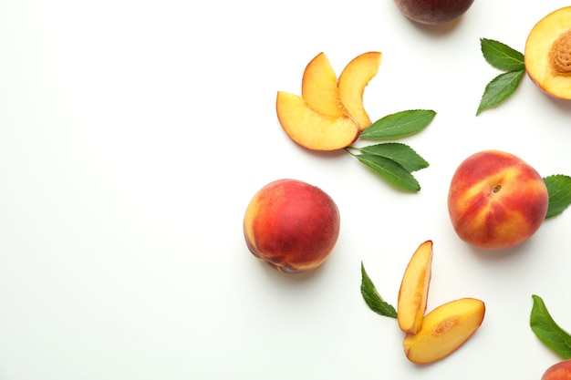 Ripe peach fruits with leaves on white background