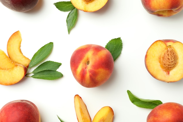 Ripe peach fruits with leaves on white background