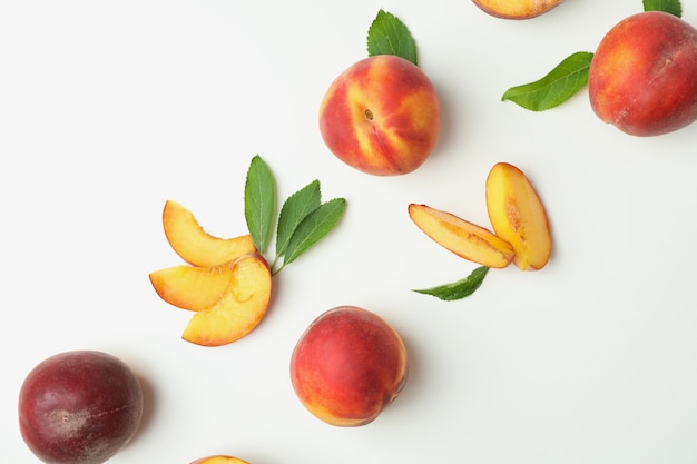 Ripe peach fruits with leaves on white background