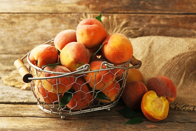 Ripe peaches in basket on wooden background