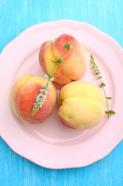 Ripe peaches on a plate on a blue background