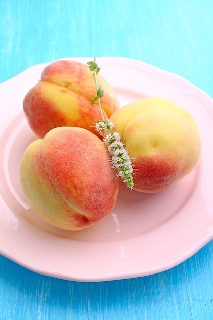 Ripe peaches on a plate on a blue background