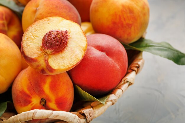 Ripe peaches in a wicker basket on a stone gray table