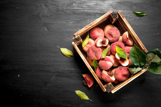 Ripe peaches in a wooden box. On the black chalkboard.