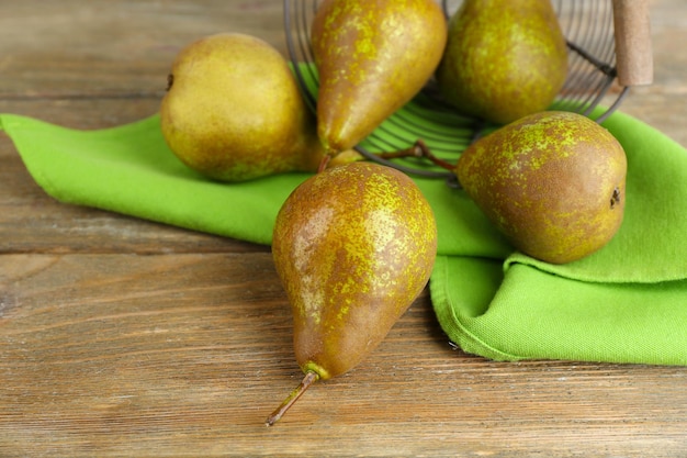 Ripe pears in basket on wooden background