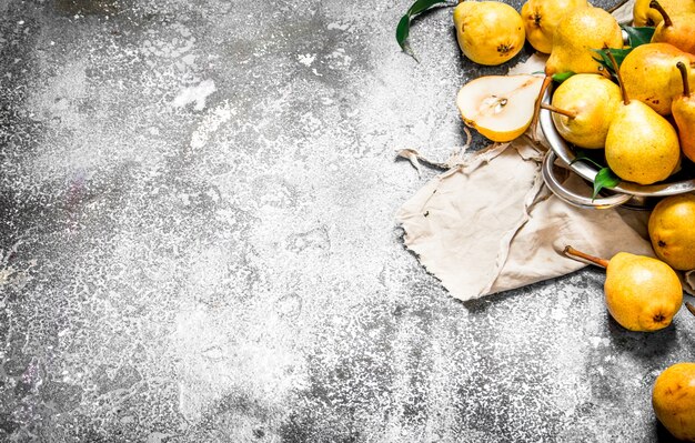 Ripe pears in a bowl on rustic table.