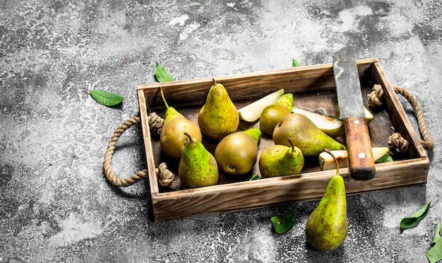 Ripe pears on a tray with an old knife. On a rustic table.