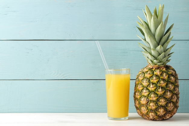 Ripe pineapple fruit and pineapple juice on a blue wooden table. place for text.