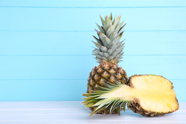 Ripe pineapple and half of pineapple on a blue wooden background